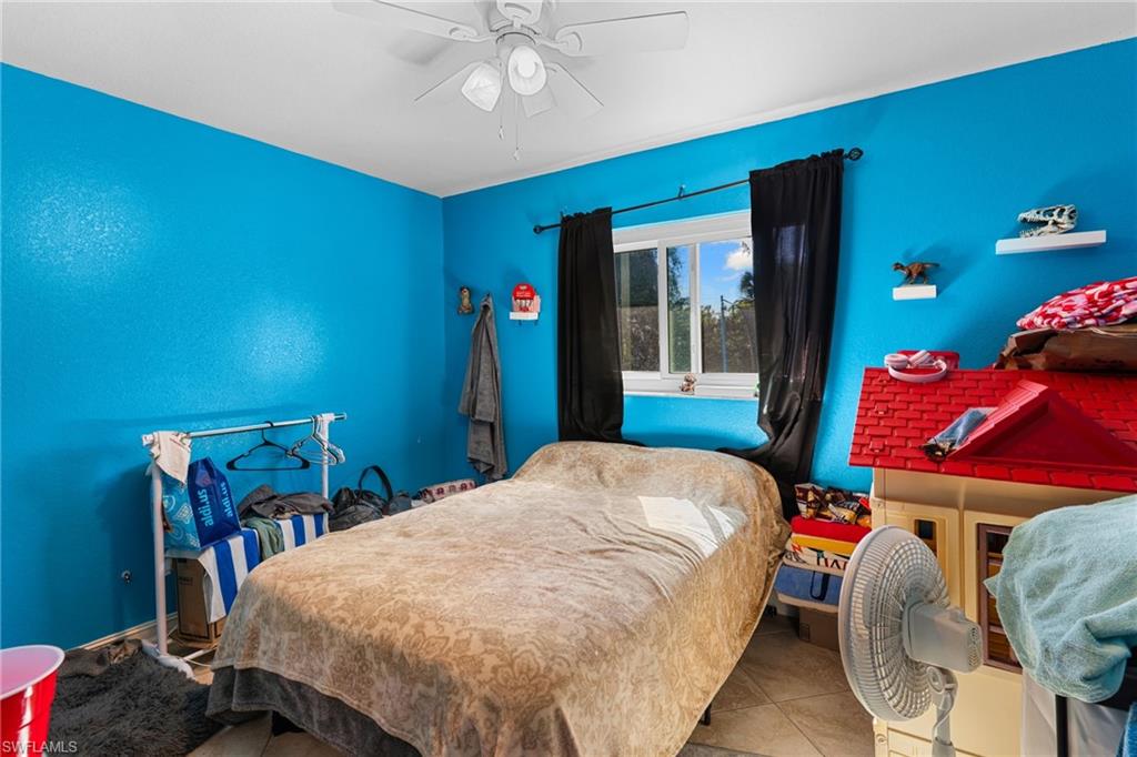 Tiled bedroom featuring ceiling fan and baseboards