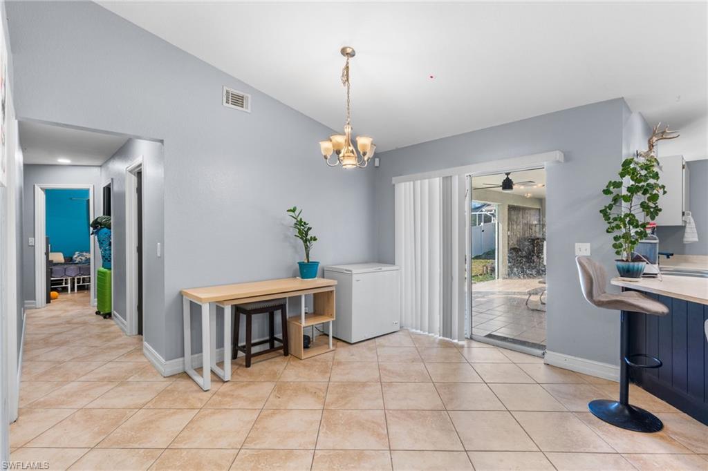 Dining area with vaulted ceiling, a chandelier, light tile patterned floors, and a ceiling fan
