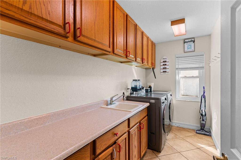 Laundry area with cabinet space, light tile patterned floors, and washer and dryer