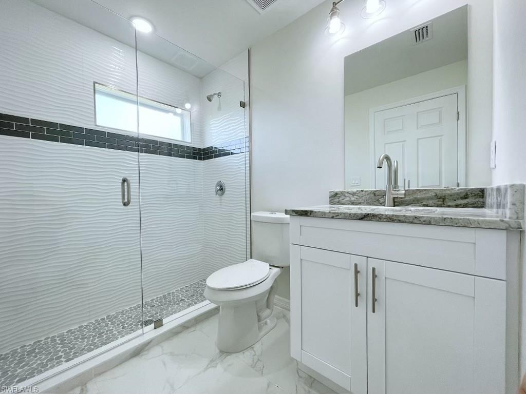 Bathroom with vanity, a shower stall, and light marble finish flooring