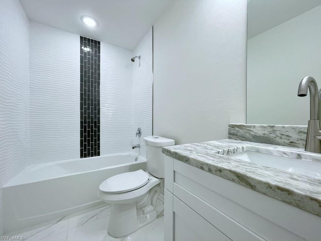 Bathroom with vanity, shower / washtub combination, light marble finish floors, and a textured wall