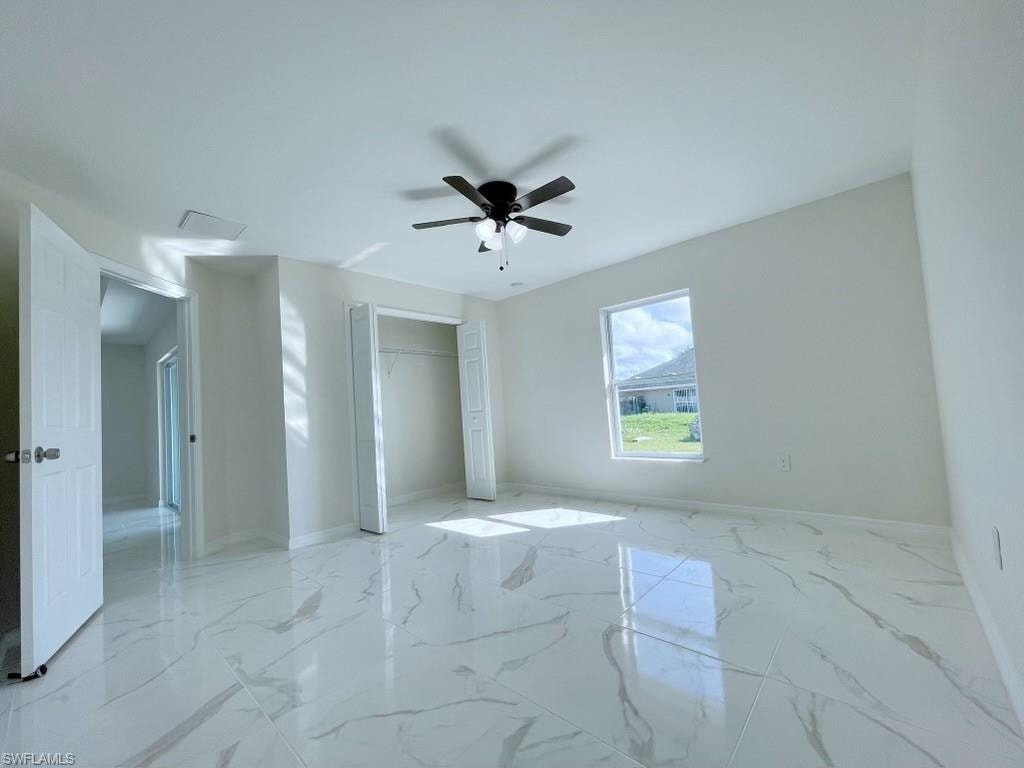 Unfurnished bedroom with a closet, a ceiling fan, and light marble finish flooring