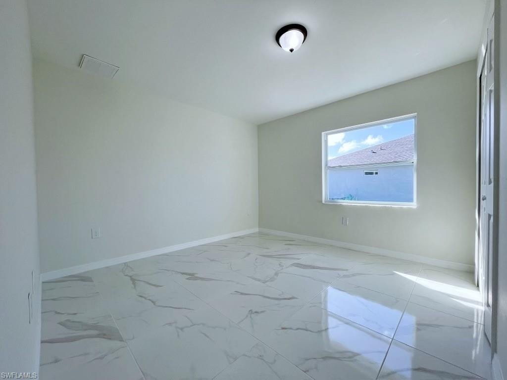 Spare room featuring baseboards and light marble finish floors