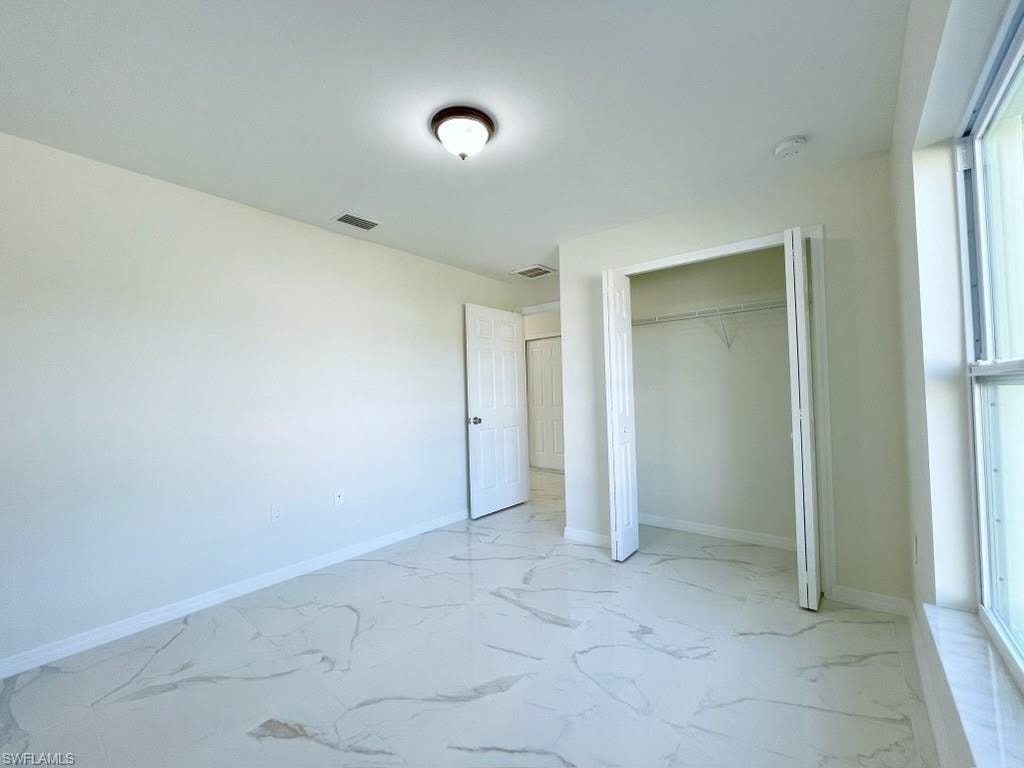 Unfurnished bedroom featuring light marble finish flooring and a closet