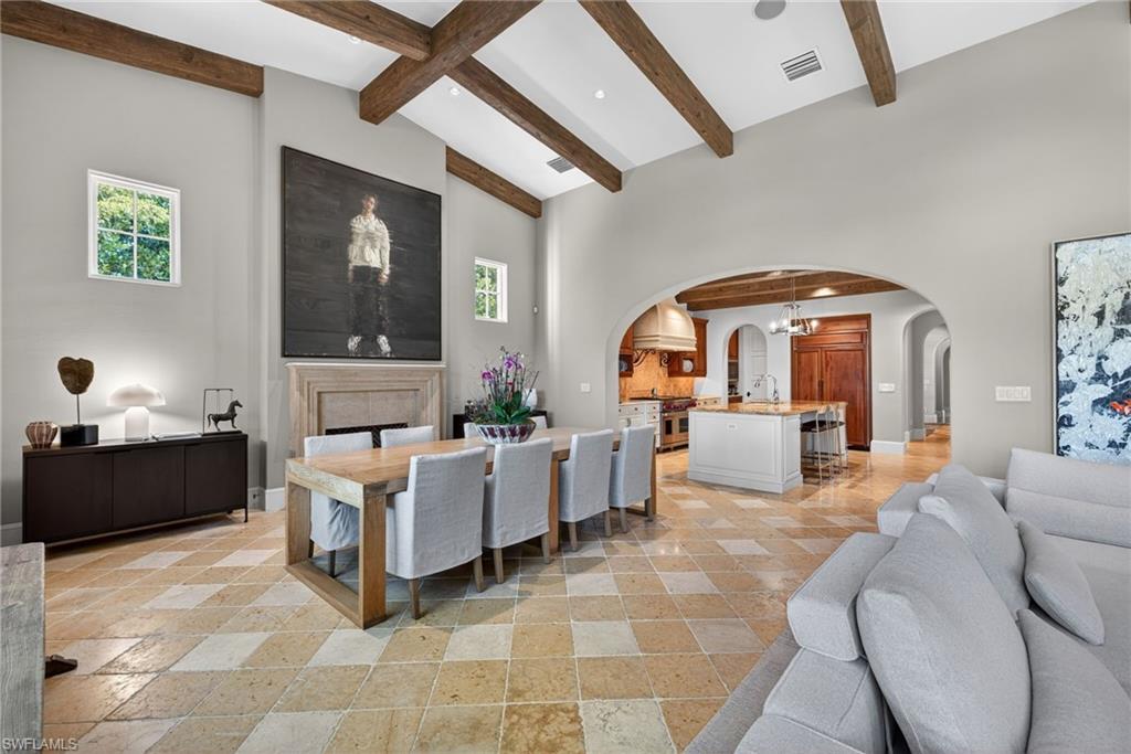 Dining area with recessed lighting, beamed ceiling, stone tile floors, arched walkways, and high vaulted ceiling