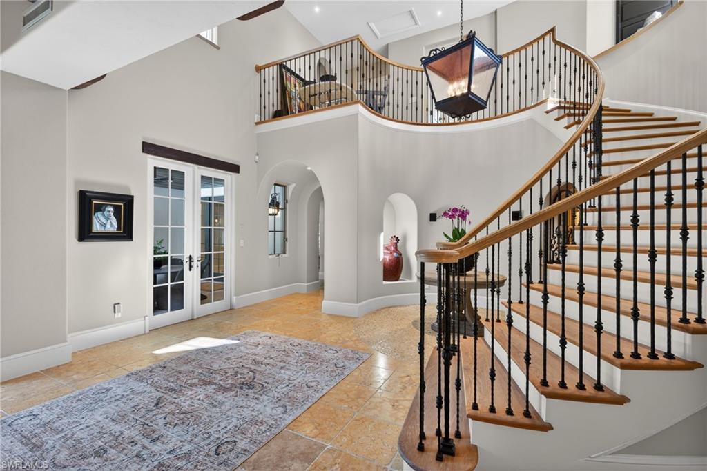 Staircase with french doors, arched walkways, and a towering ceiling