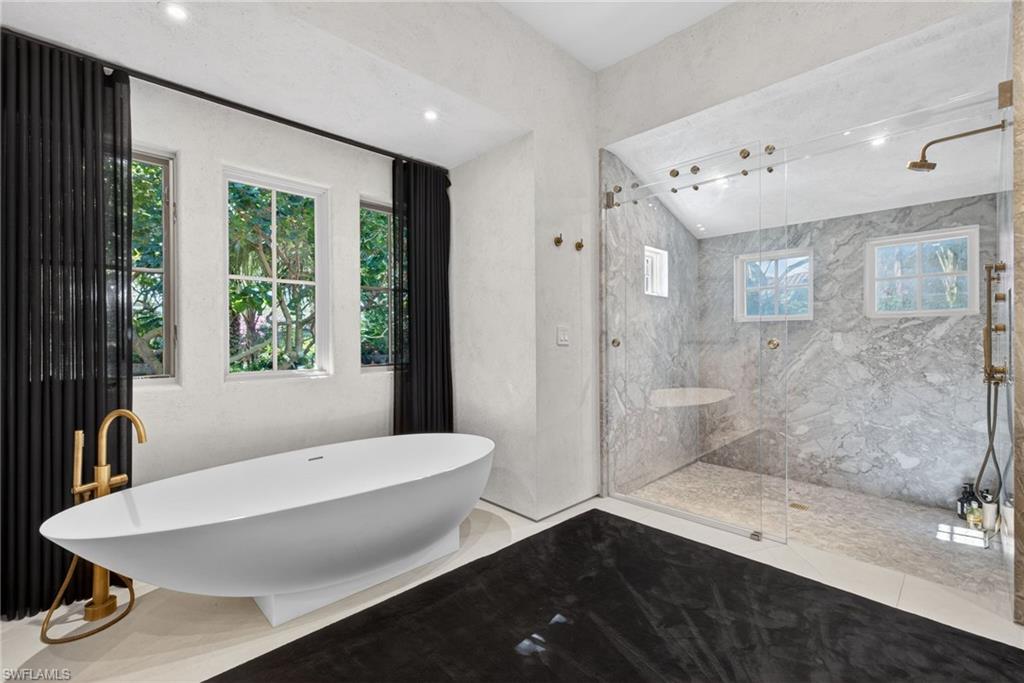 Bathroom with a freestanding tub and a marble finish shower