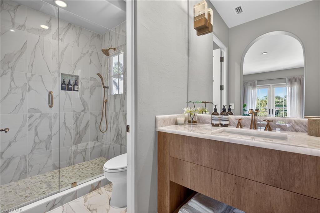 Full bathroom with a marble finish shower, light marble finish flooring, vanity, and plenty of natural light