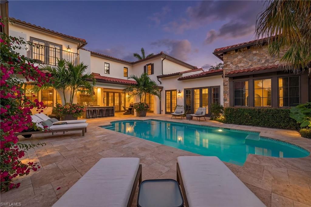 Pool at dusk featuring an outdoor pool, a patio, french doors, and a balcony