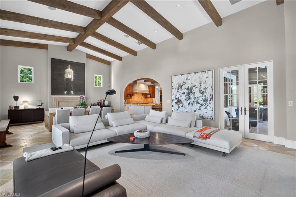 Living area with stone tile floors, arched walkways, french doors, plenty of natural light, and high vaulted ceiling