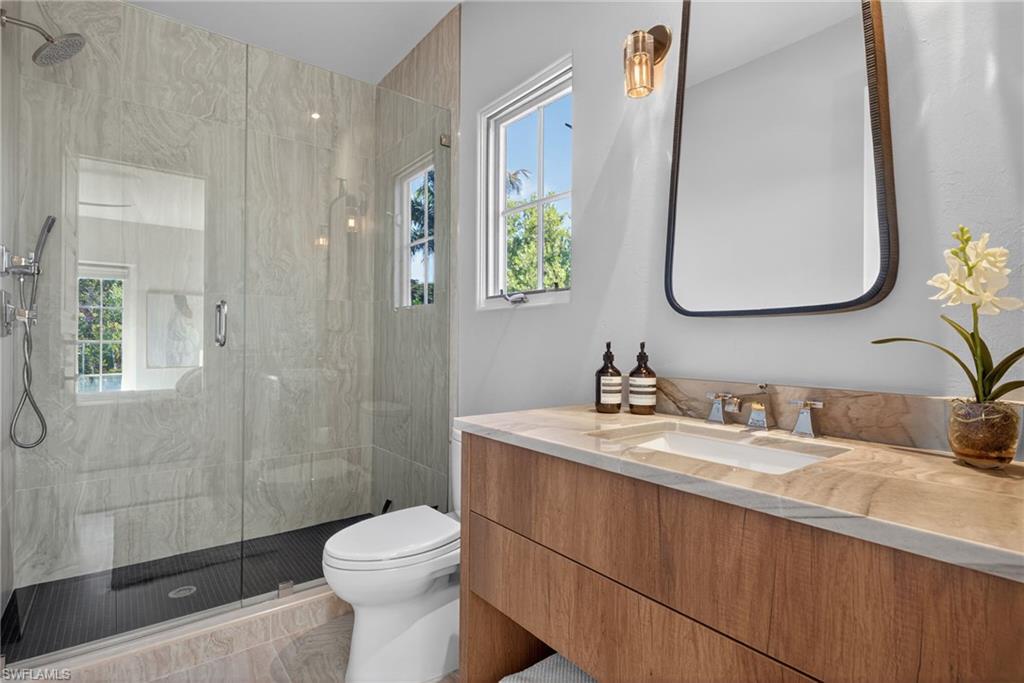 Full bathroom with healthy amount of natural light, a marble finish shower, and vanity