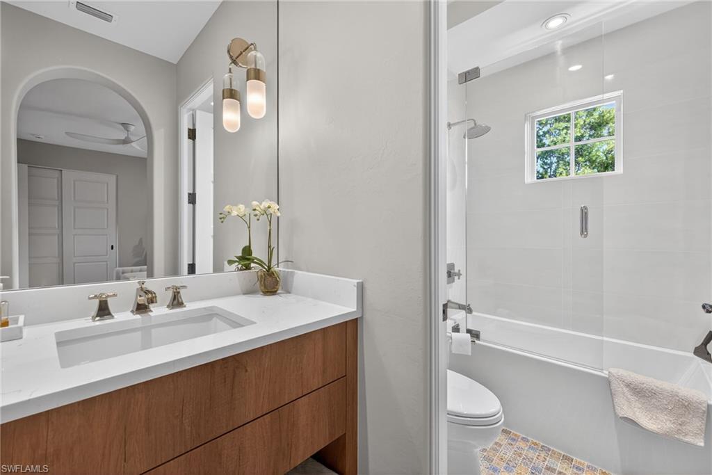Bathroom with bath / shower combo with glass door and vanity