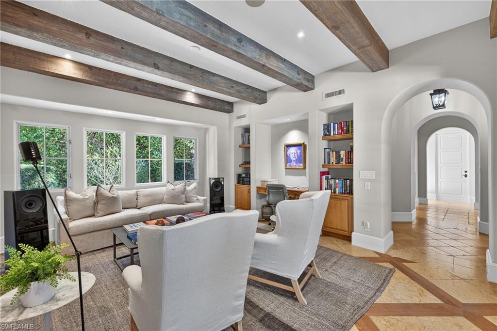 Living room featuring a desk, arched walkways, inlaid floor details, built in shelves, and recessed lighting