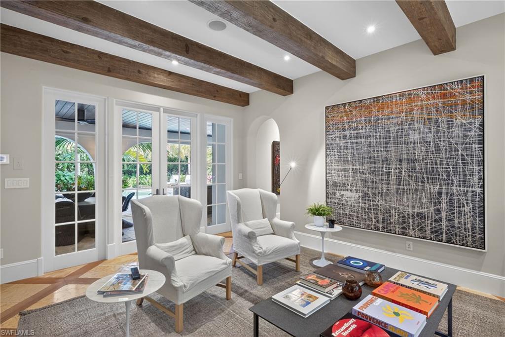Living room featuring french doors, recessed lighting, inlaid floor details, arched walkways, and beam ceiling