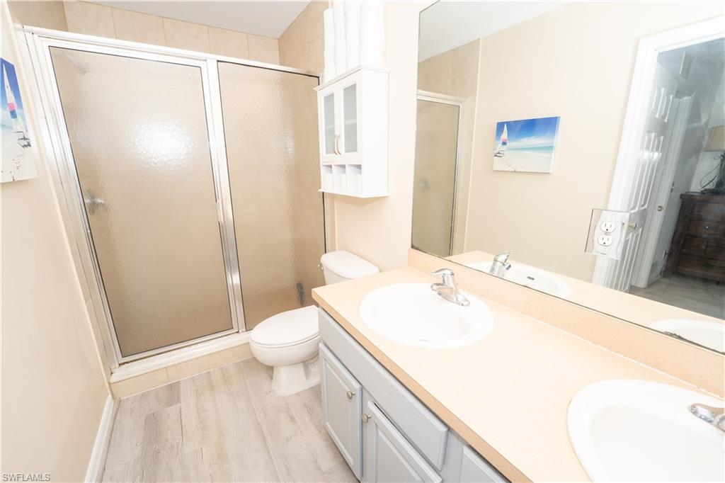 Full bathroom with a stall shower, double vanity, and light wood finished floors