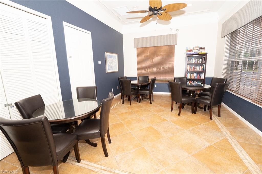 Dining space with light tile patterned flooring, a raised ceiling, ornamental molding, and ceiling fan