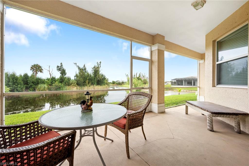 Sunroom with a water view, a textured wall, and concrete floors