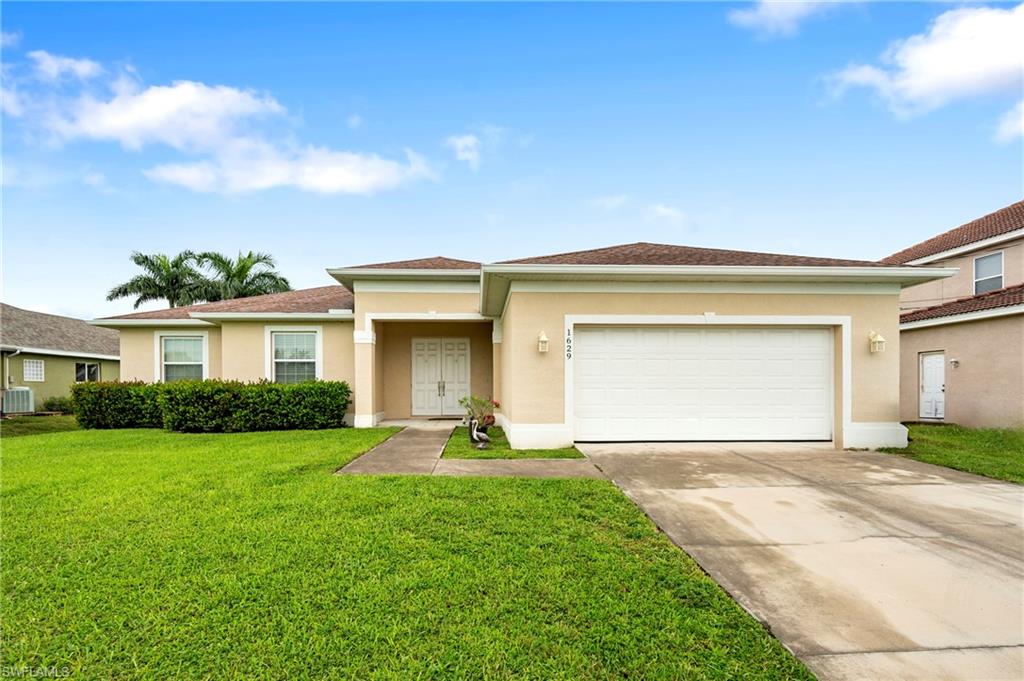 View of front of home featuring stucco siding, a front yard, driveway, and a garage