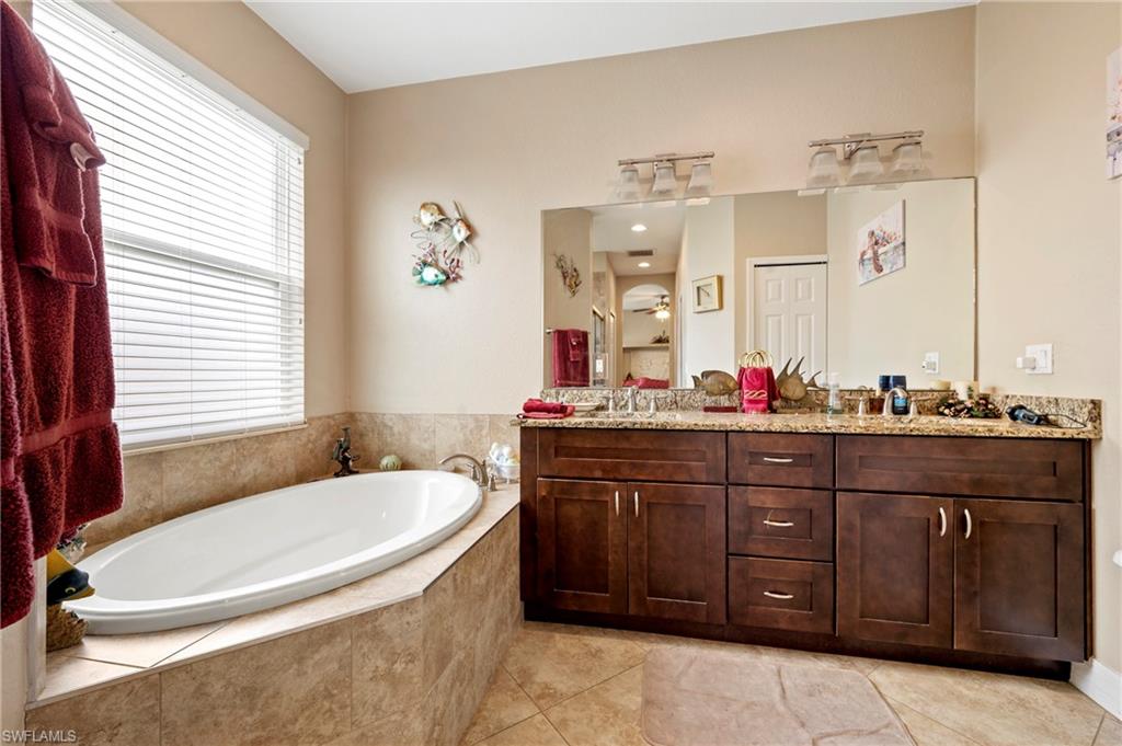 Full bath with a bath, double vanity, light tile patterned floors, and a ceiling fan