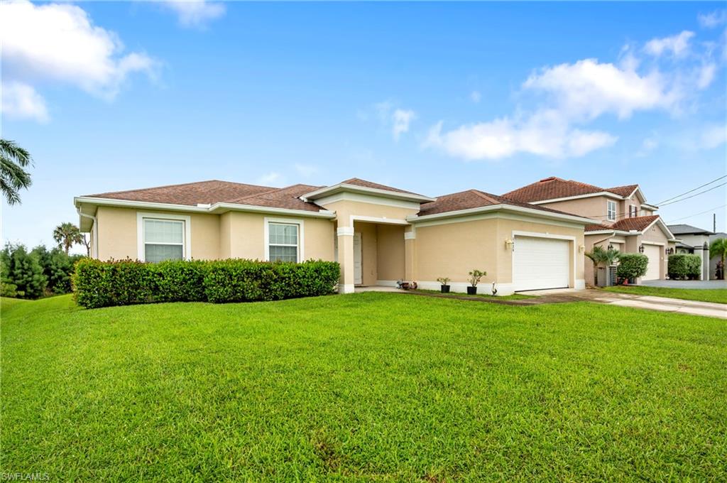 View of front of house with stucco siding, concrete driveway, a front lawn, and a garage
