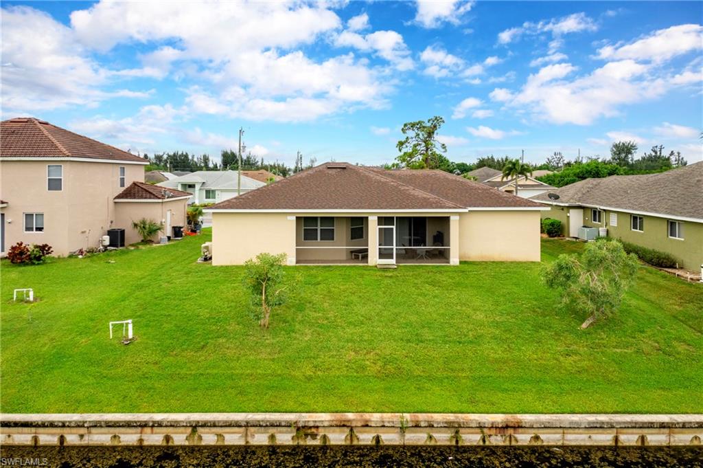 Back of property with stucco siding, a lawn, a sunroom, a residential view, and a shingled roof