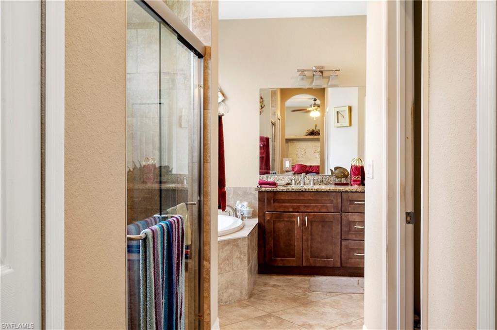 Full bath with vanity, a stall shower, a garden tub, ceiling fan, and light tile patterned flooring