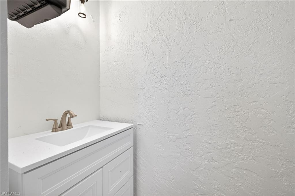 Bathroom with a textured wall and vanity