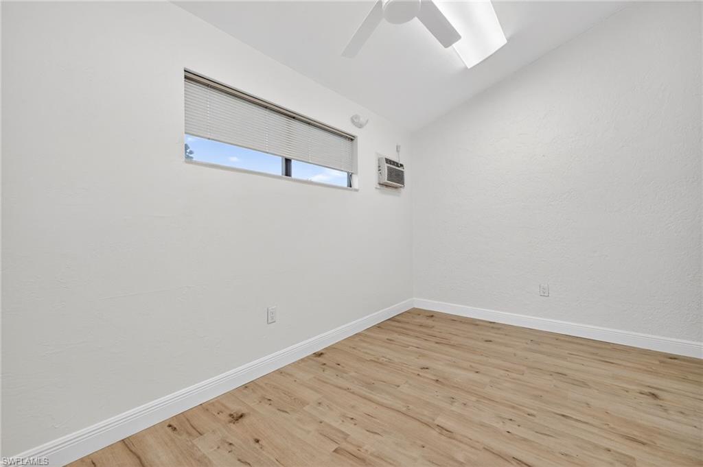 Spare room with lofted ceiling, wood finished floors, a textured wall, and a wall unit AC