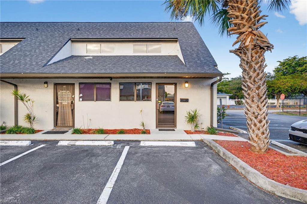 View of front of house with uncovered parking, roof with shingles, and stucco siding