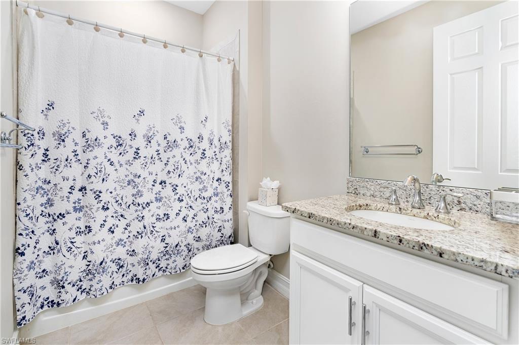 Bathroom with vanity, light tile patterned flooring, and shower / bath combo with shower curtain