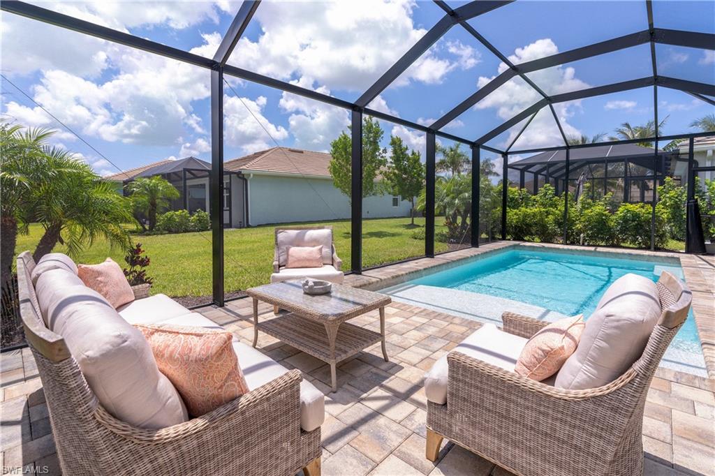 Swimming pool featuring a sunroom, a lawn, and a patio area