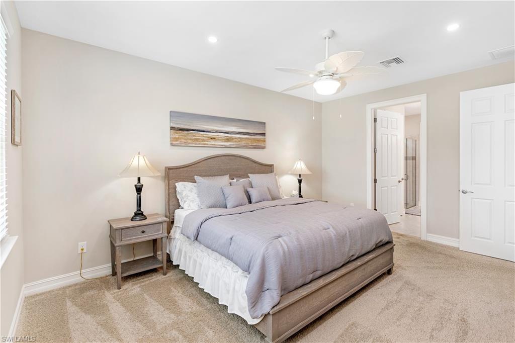 Bedroom featuring light carpet, recessed lighting, ceiling fan, and ensuite bath