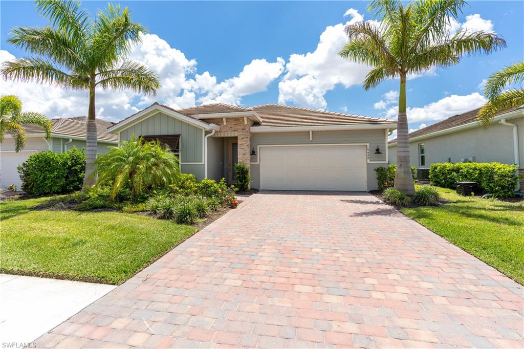 Ranch-style house featuring a front yard, a tiled roof, decorative driveway, and a garage