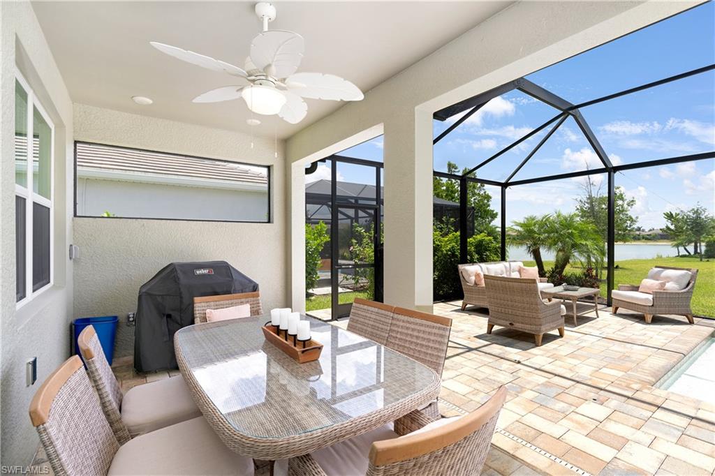 View of patio featuring a ceiling fan, a water view, a sunroom, glass enclosure, and an outdoor hangout area
