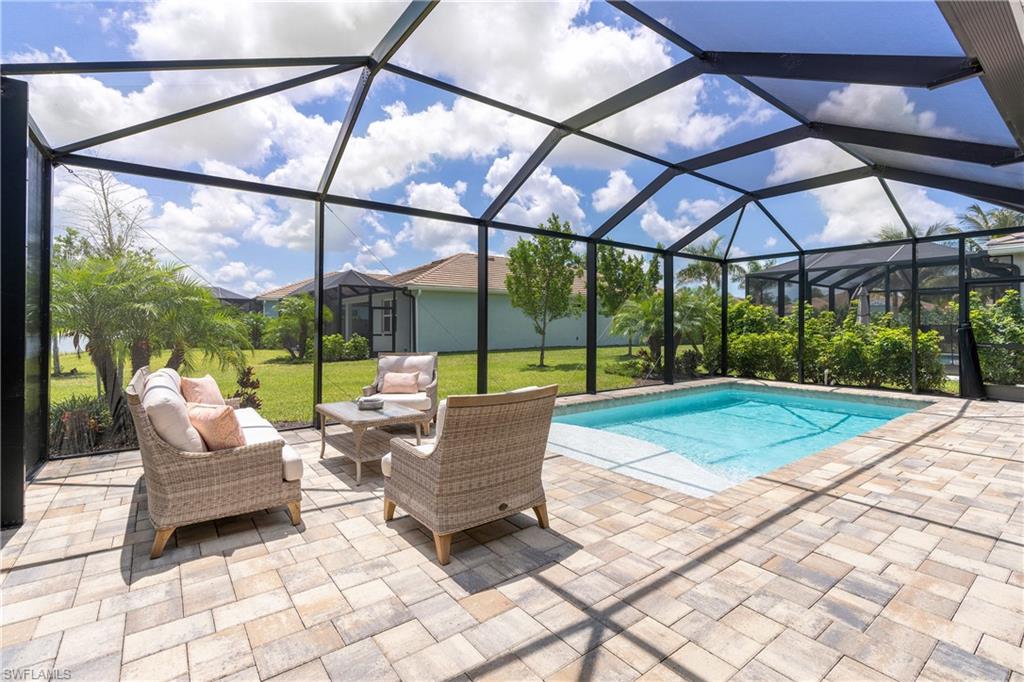 Outdoor pool with glass enclosure, a sunroom, a patio area, and a yard