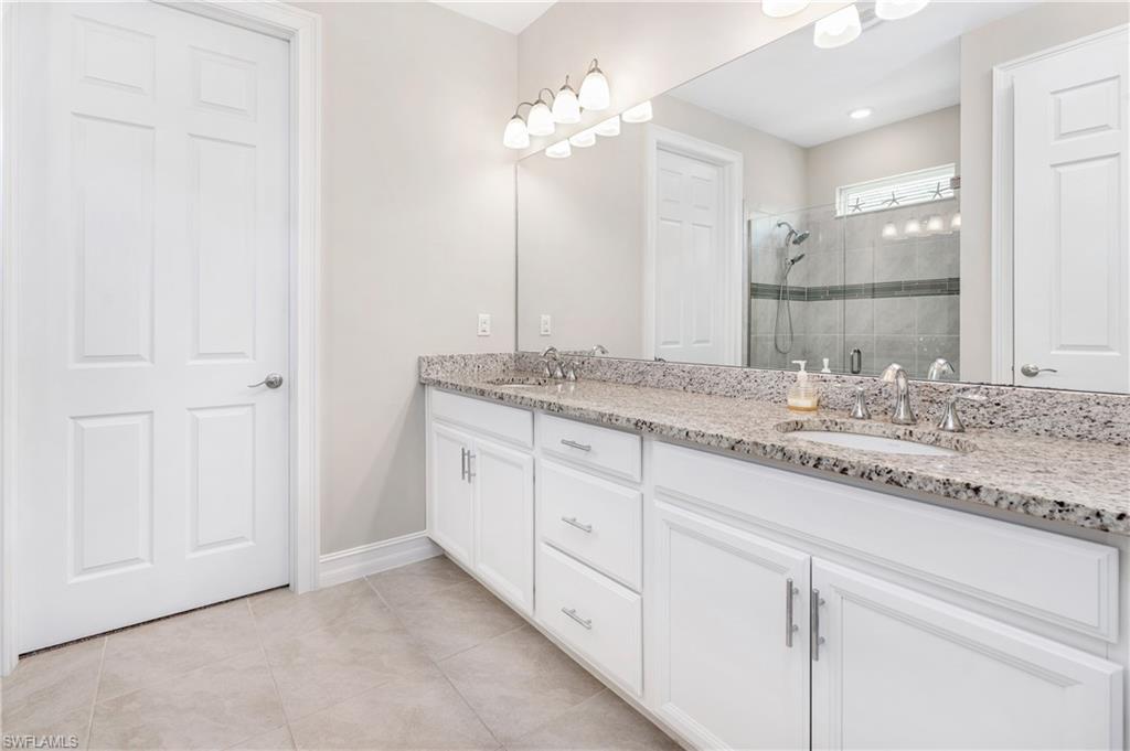 Bathroom with double vanity, a stall shower, and light tile patterned floors