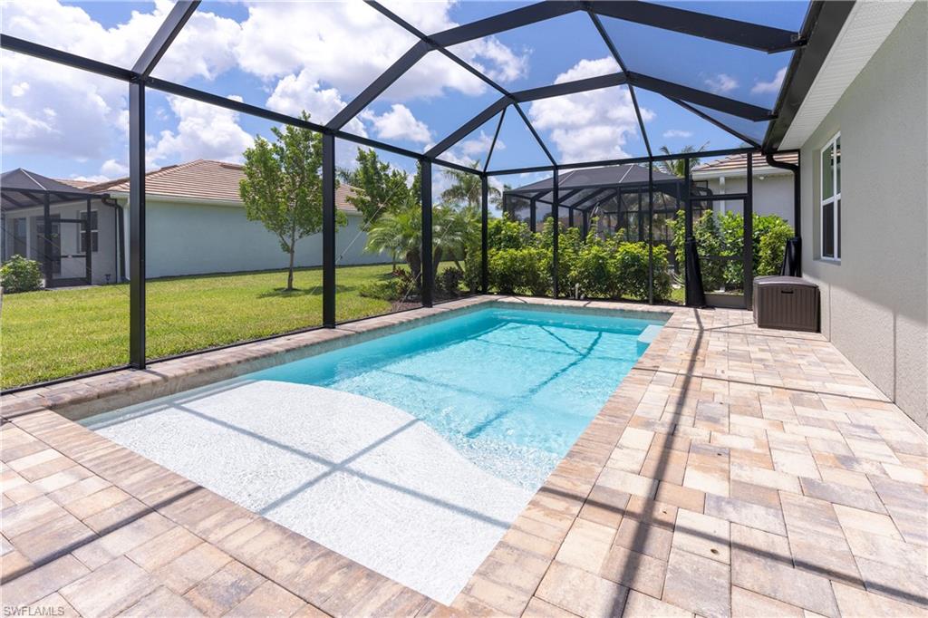 Outdoor pool with a sunroom, a lawn, a lanai, and a patio