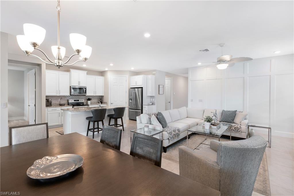 Living room with a chandelier, a decorative wall, recessed lighting, ceiling fan, and light tile patterned floors