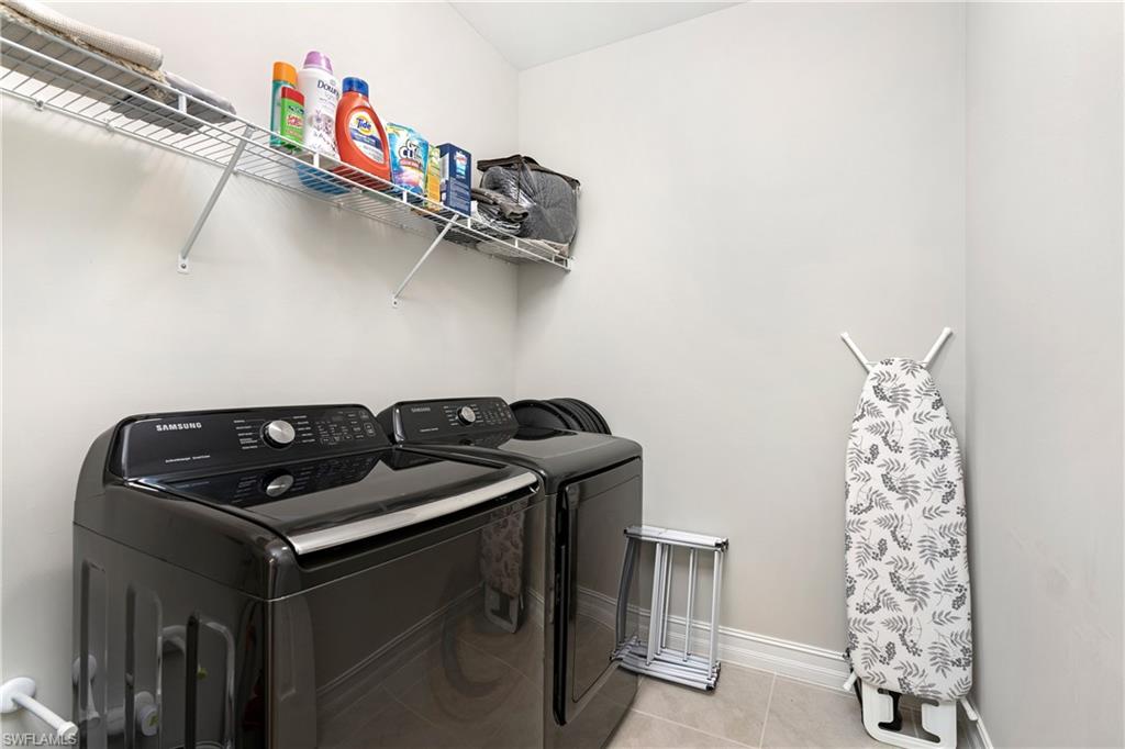 Laundry area featuring light tile patterned floors and washing machine and dryer