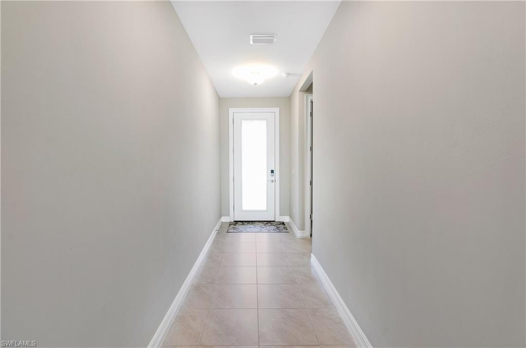 Doorway to outside featuring tile patterned floors and baseboards
