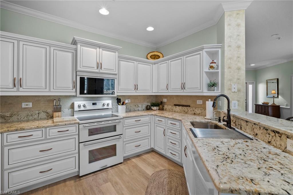 Kitchen with range with two ovens, open shelves, light stone counters, white cabinets, and ornamental molding