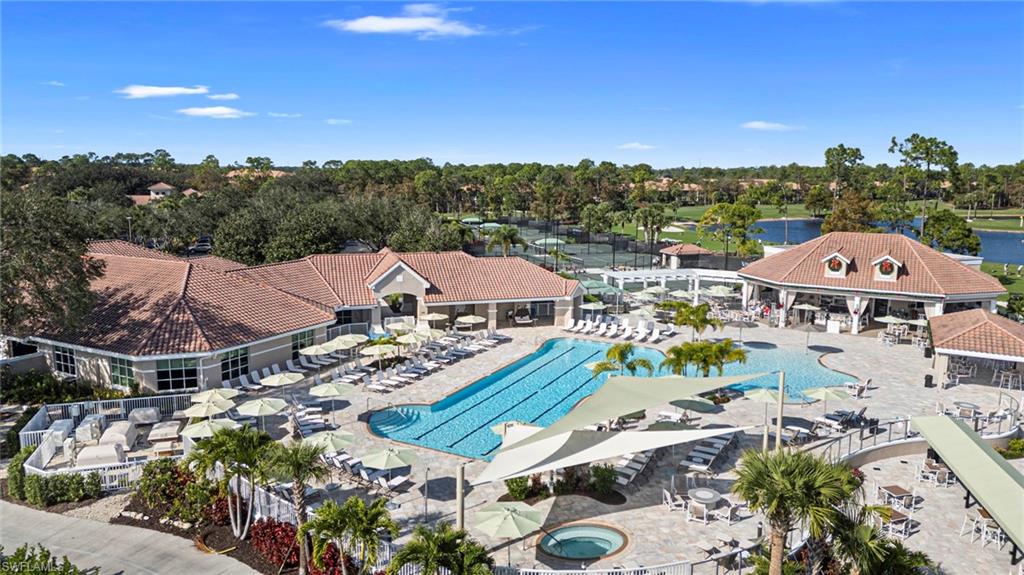 Community pool featuring a patio, view of wooded area, and a water view