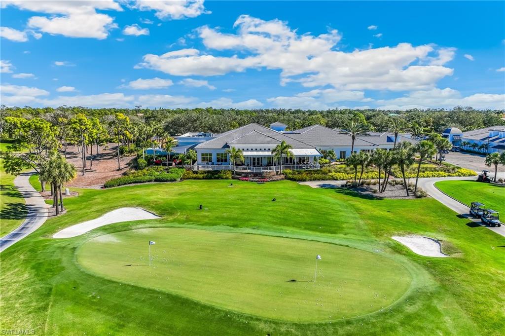 View of property's community featuring golf course view, a yard, and an area to practice putting