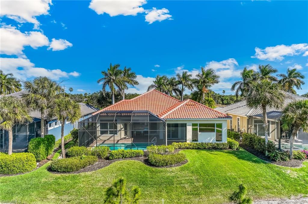 Rear view of house featuring a lanai, an outdoor pool, a tile roof, a sunroom, and a lawn