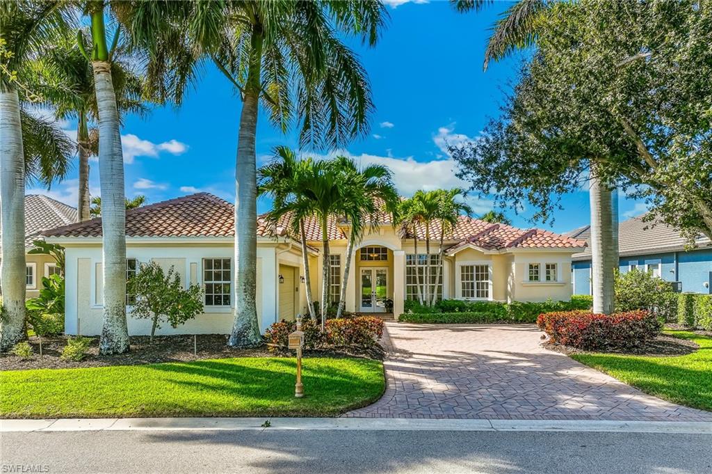 Mediterranean / spanish home with stucco siding, a front lawn, driveway, and a tile roof