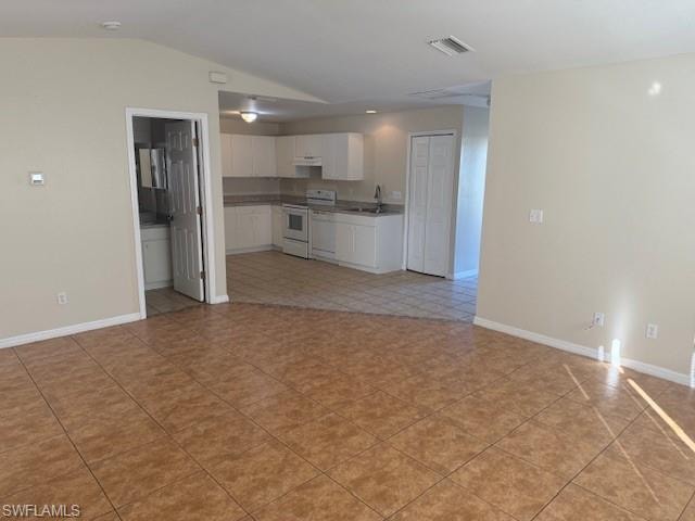 Kitchen featuring white cabinetry, open floor plan, white appliances, vaulted ceiling, and light tile patterned flooring
