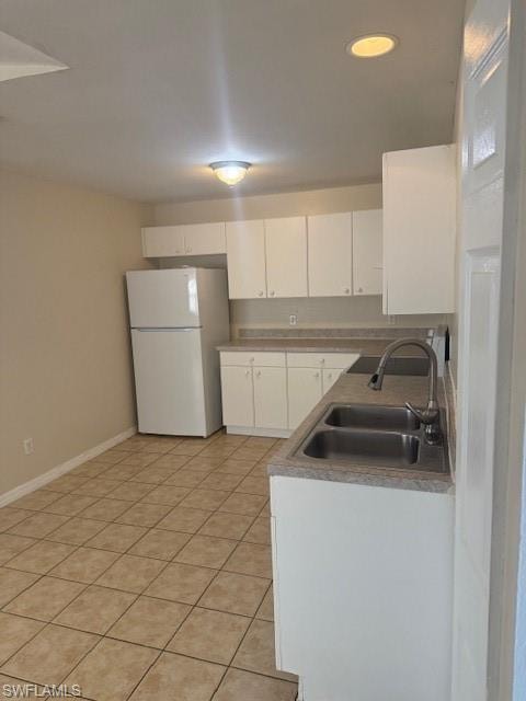 Kitchen with fridge, white cabinets, and light tile patterned floors
