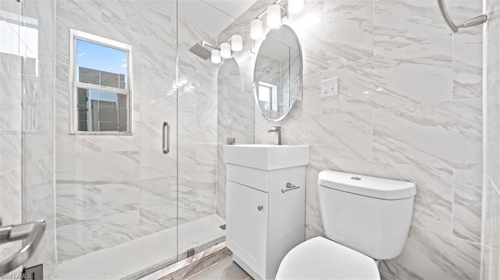 Full bathroom featuring tile walls, vanity, and a marble finish shower