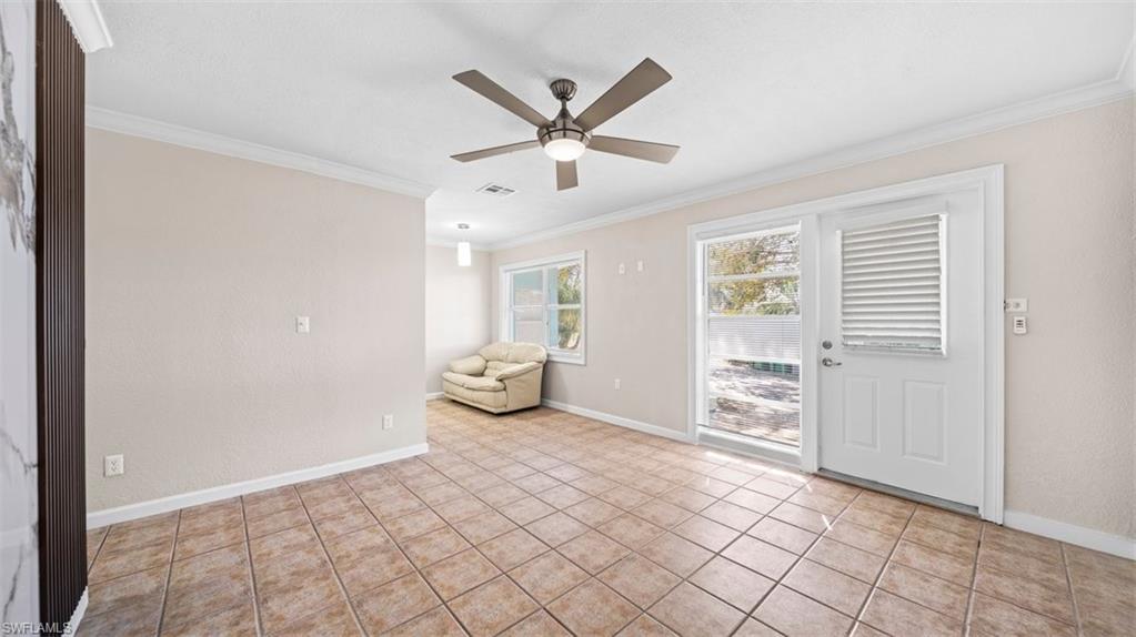 Unfurnished room with ornamental molding, light tile patterned floors, and a ceiling fan