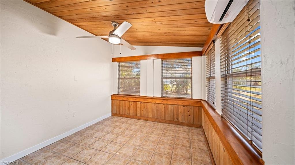 Unfurnished sunroom with vaulted ceiling and a wall unit AC